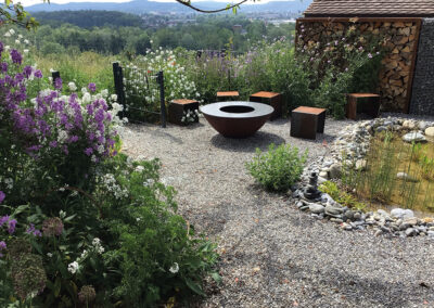 Der Sitzplatz mit Feuerschale ist harmonisch in den Garten der Familie Bucher eingebettet. Im Juni blühen die Mondviolen und verströmen jeweils abends ihren süsslichen Duft.